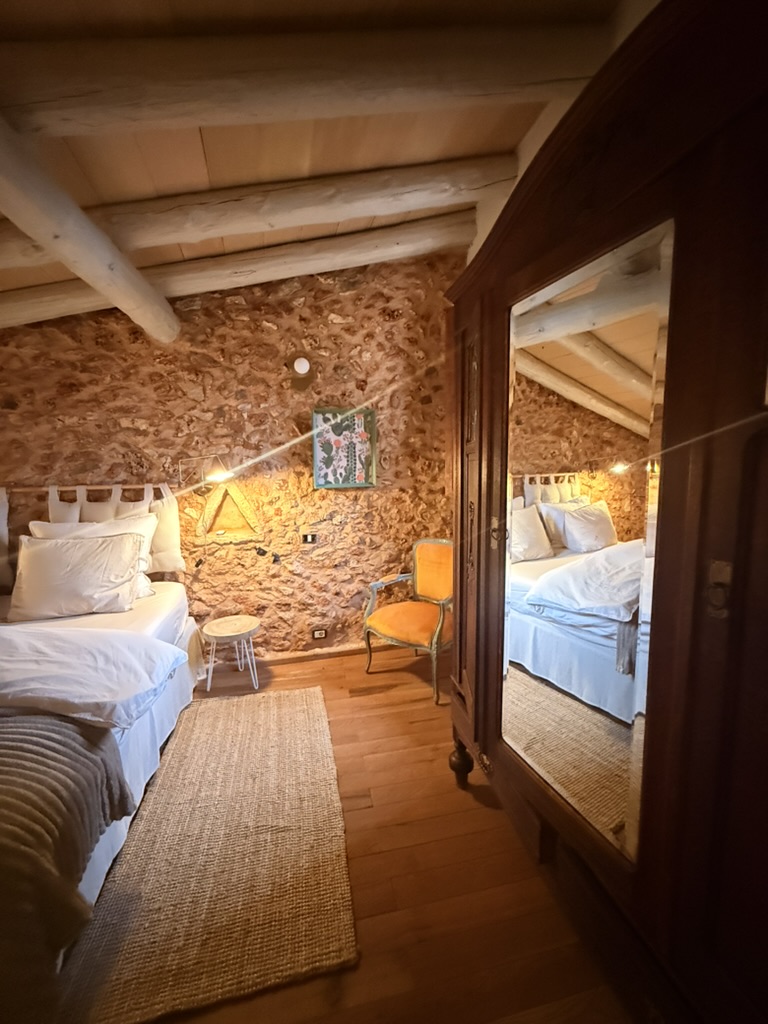 Schlafzimmer mit antikem Spiegel und Natursteinwand